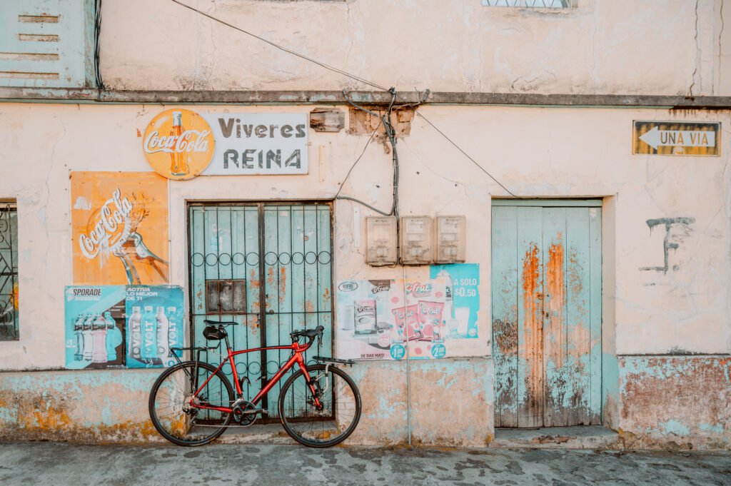 A red road bike leans against a closed shop covered in faded and peeling signs in Tulcán, Ecuador. Pic by Ben Finch