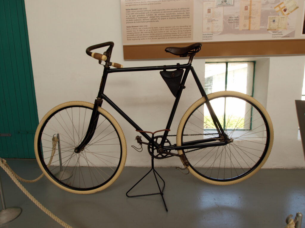A black Laurin & Klement Slavia bicycle from 1896 hangs in a museum. It has white tyres.