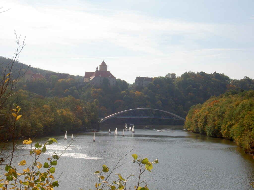 Veveří Castle can be seen across Brno reservoir, which is full of small boats.