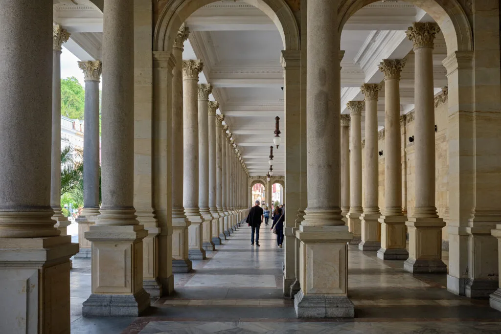 People walk through the Mill Colonnade flanked by huge pillars in Karlovy Vary.