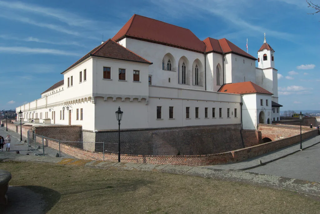 Hrad Špilberk is a white castle with a red roof surrounded by a moat in Brno