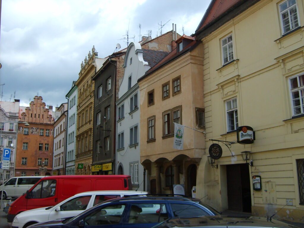 Cars are parked outside buildings in Plzen, near the entrance to the historic underground