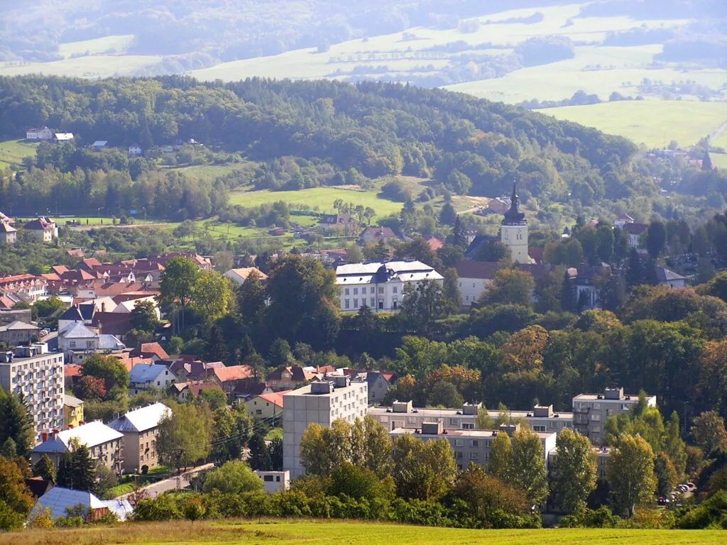 A wide shot of Vizovice showing the town and it's grand castle, set against green fields and woods.