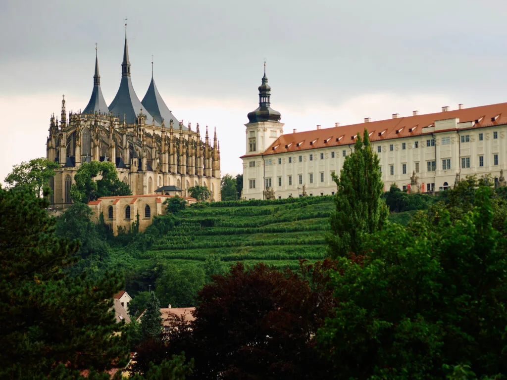 An ancient church and monastery sit on top of a green hill in Kutná Hora.
