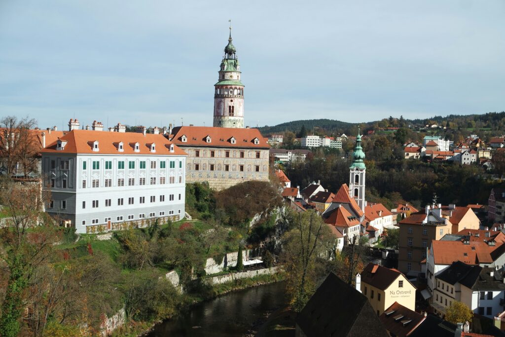 The tower of a castle dominates the skyline of a red-roofed city surrounded by forest. Wheely Tyred Český Krumlov attractions