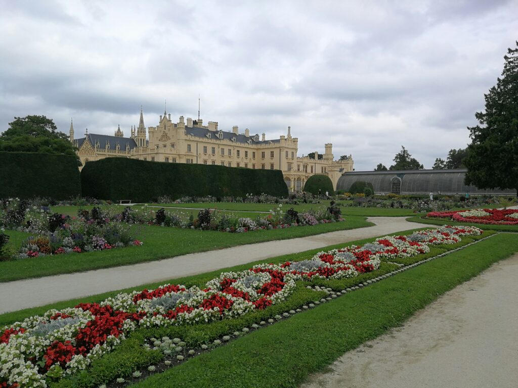 A cream chateau rises over manicured gardens in Lednice