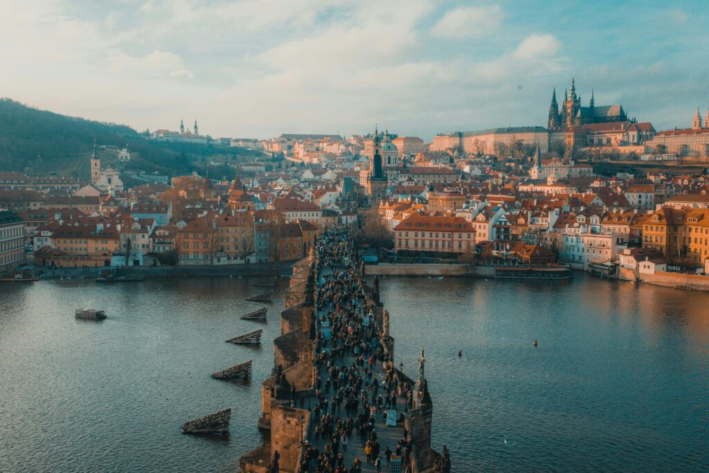 Thousands of people cross the Charles Bridge, walking towards the Castle and St Vitus Cathedral on a clear day.