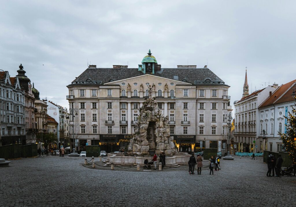 A fountain in Zelný trh in Brno in front of a large Baroque building. Wheely Tyred best time to visit Brno
