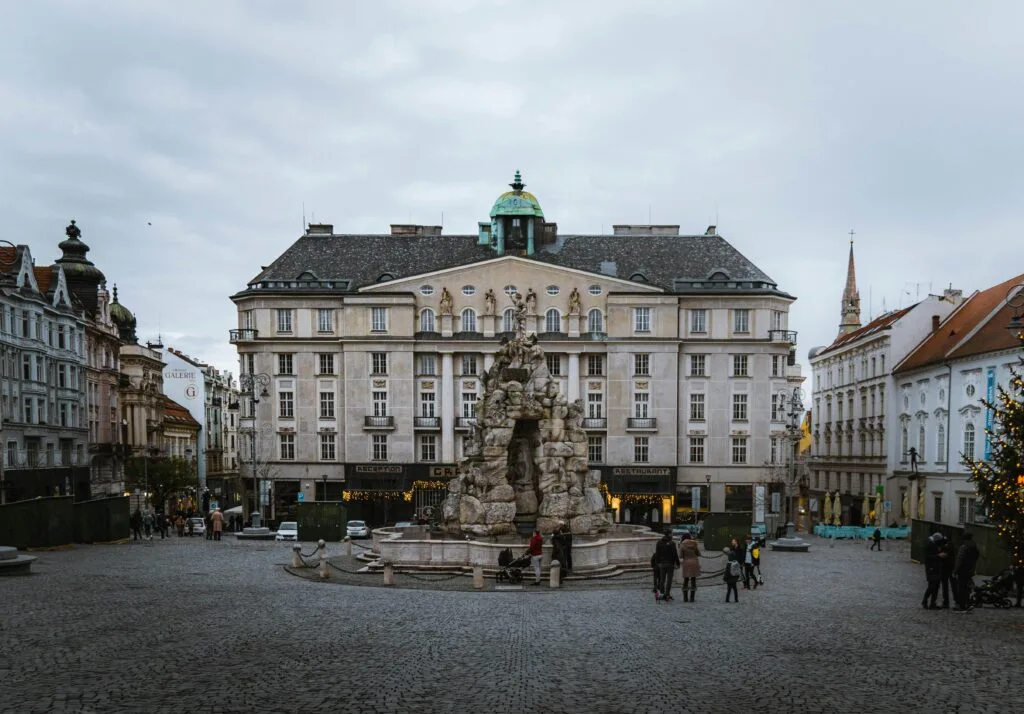 A fountain in Zelný trh in Brno in front of a large Baroque building. Wheely Tyred best time to visit Brno