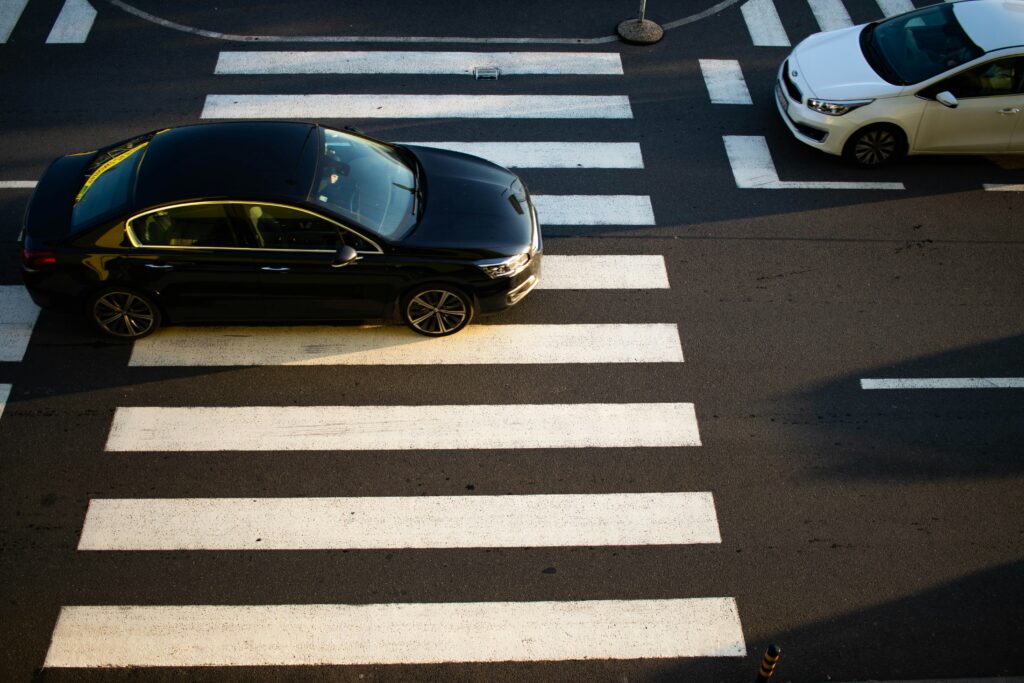 A balck car sits in a zebra crossing, rude and entitled.