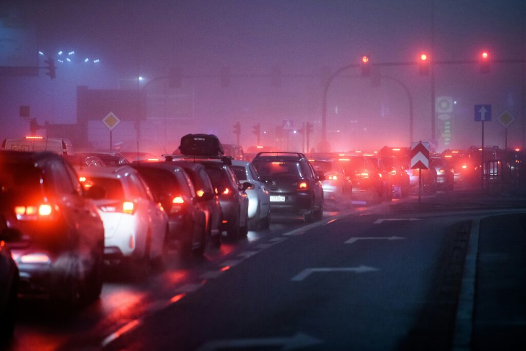 The red taillights of cars stretch into the distance on a foggy day, it's a traffic jam.