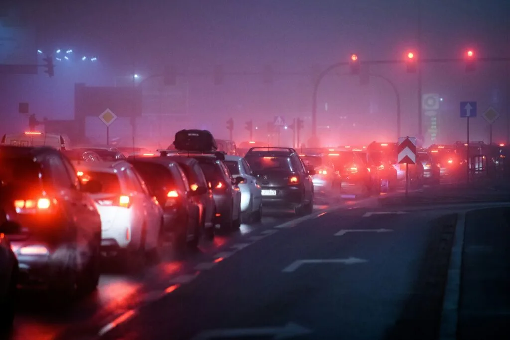 The red taillights of cars stretch into the distance on a foggy day, it's a traffic jam.