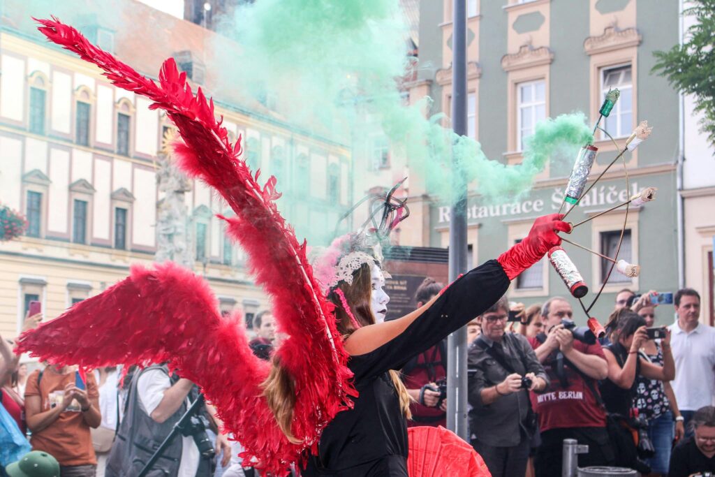 A woman dressed as a harlequin sprays green smoke at a carnival in Brno, Czechia. Wheely Tyred best time to visit Brno