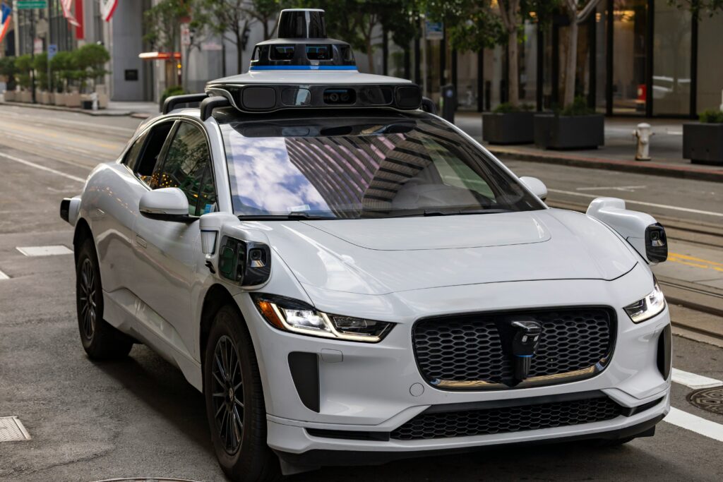 A white autonomous car is covered with sensors so it can see where it is going.
