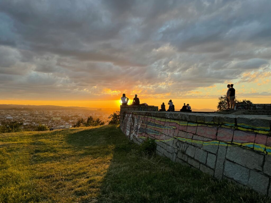 People watch sunset from on of the hills in summer in Brno.