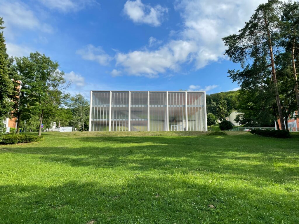A modern, functionalist glass building in a park. It's the Tomáš Baťa Memorial in Zlin.