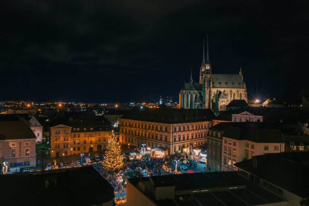 The Cathedral of St Peter and Paul stands over Zelný trh in Brno at Christmas. The square is full of people and a tree, lit up. Wheely Tyred best time to visit Brno
