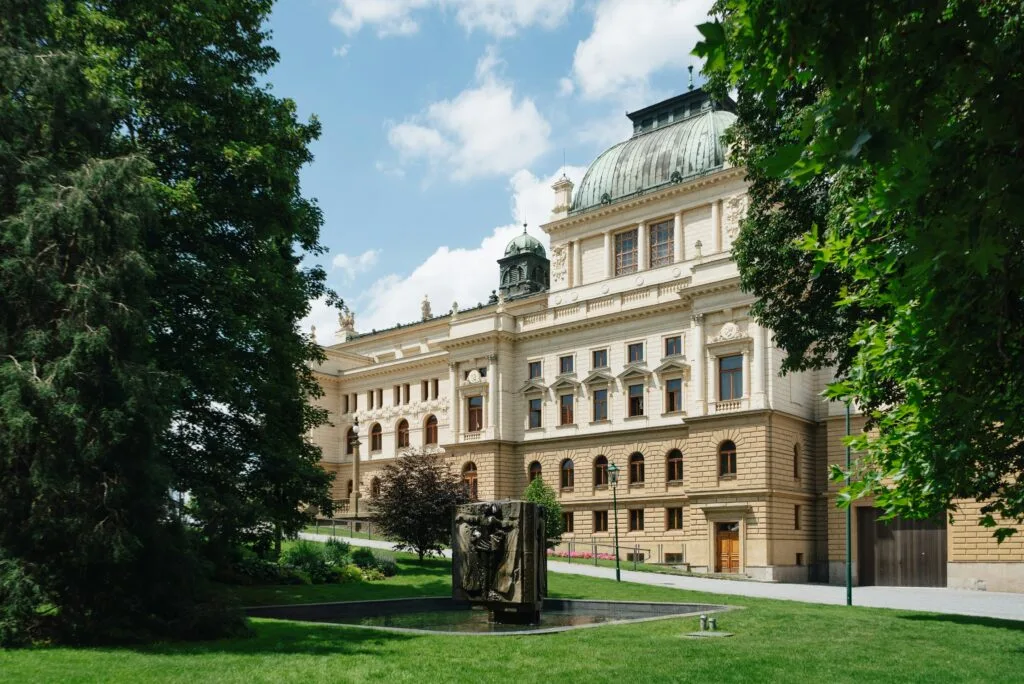 A sculpture sits in a fountain inside of a large Baroque building in Plzeň.