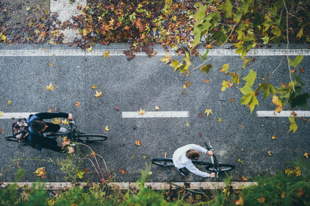 Two cyclists ride along a bike lane, seen from above.
