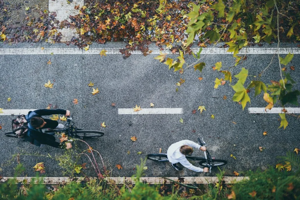 Two cyclists ride along a bike lane, seen from above.
