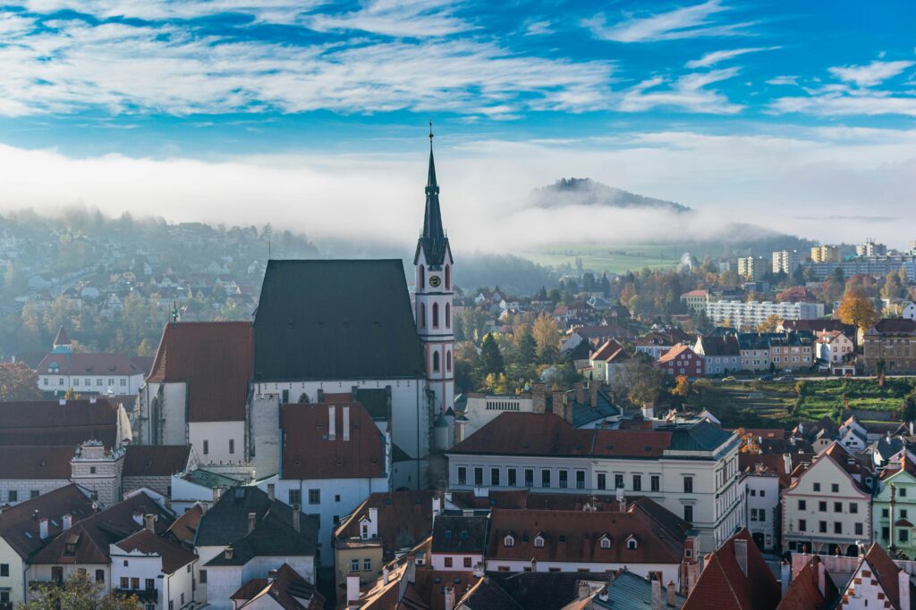 St Vitus Church is framed by mountains and fog in the early morning sunlight in Český Krumlov, Czechia