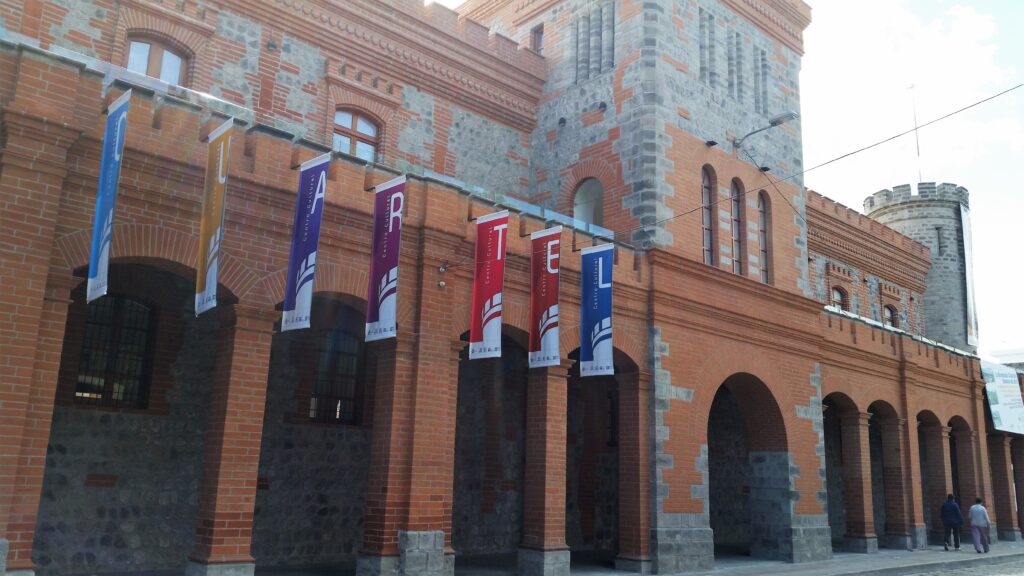 Flags fly outside the red brick Centro Cultural El Cuartel Museum in Ibarra.