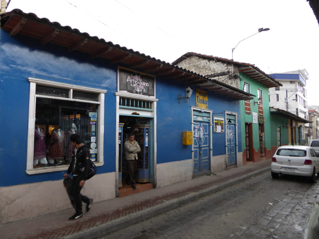 A man walks past a blue colonial building on Calle Lourdes, Loja, Ecuador