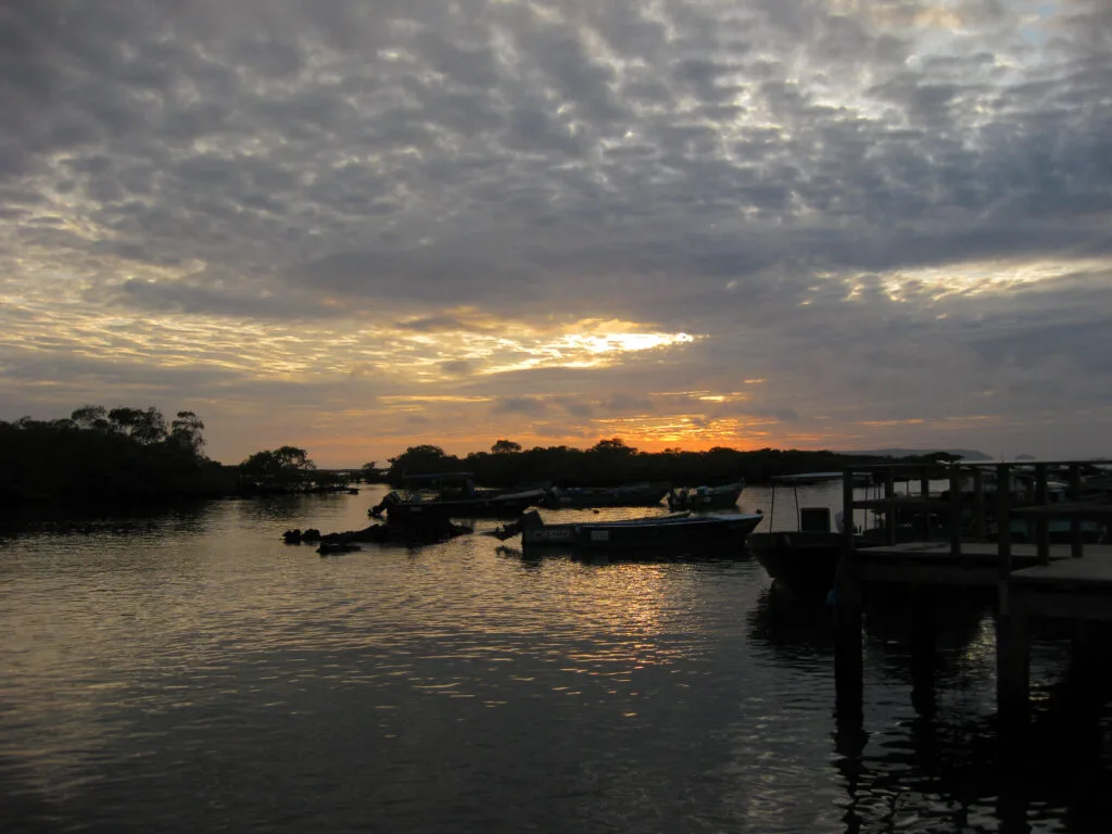 The sun sets over the docks in Puerto Villamil.