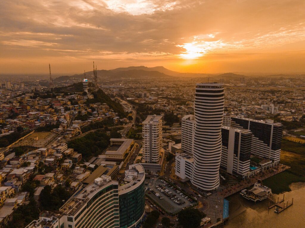 The sun sets over Guayaquil, Ecuador. A skyscraper climbs out of the seafront.