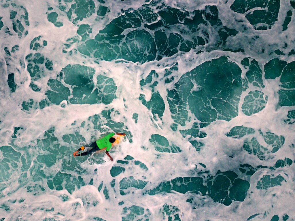 A man poddles his surfboard through the waves in Montanita, Ecuador.