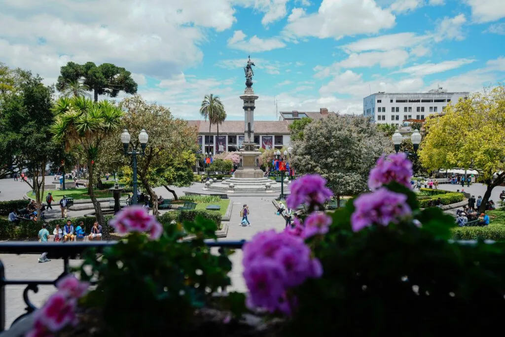 The Monumento a la Independencia in Plaza Grande in Quito's Historic Centre. It's a clear day and the plaza is full of flowers and people.