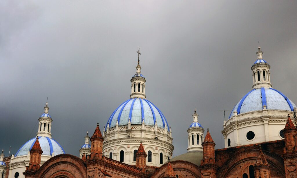 Dark clouds gather over the blue and white domes of the second cathedral in Cuenca, Ecuador. Wheely Tyred Best Time to Visit Cuenca