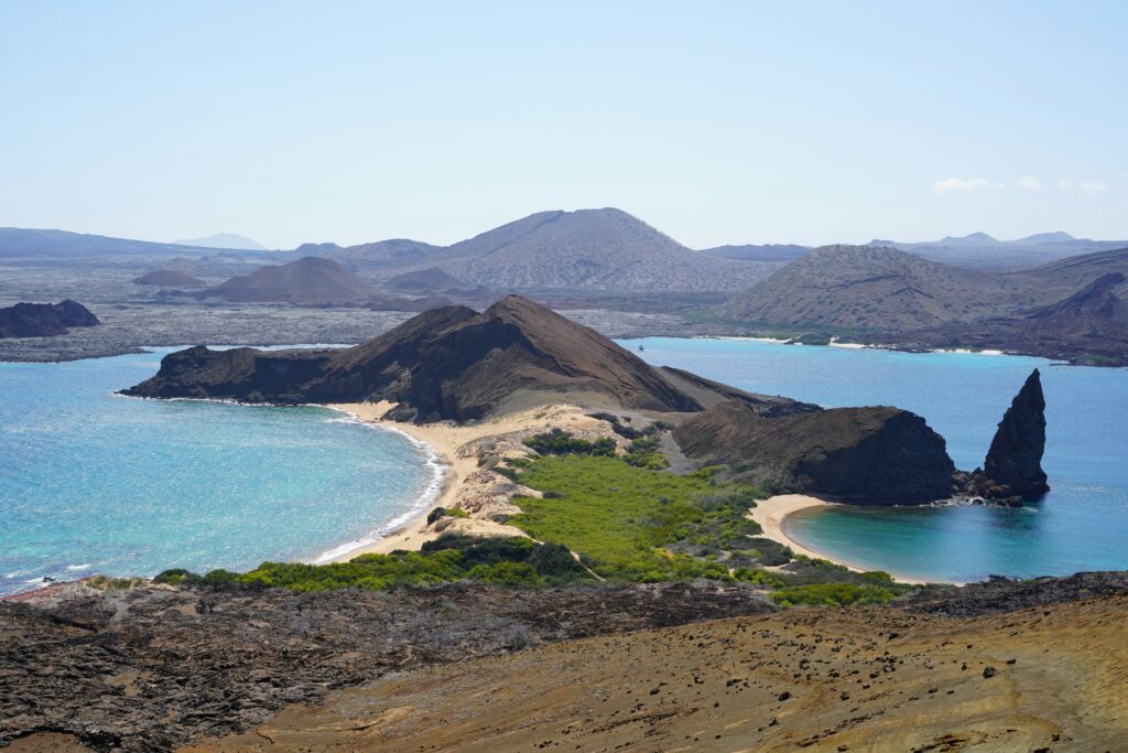 A peninsula of volcanic rock with Pinnacle Rock on display. Wheely Tyred Best Time to Visit the Galápagos Islands
