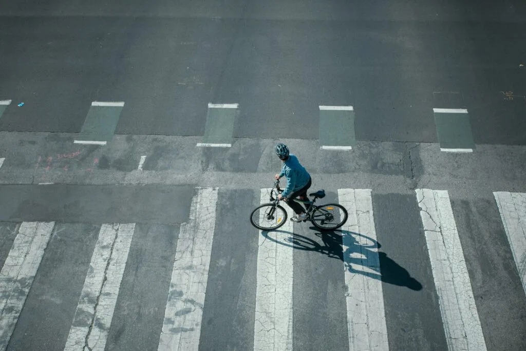 An person rides an e-bike across a zebra crossing. Wheely Tyred safe streets