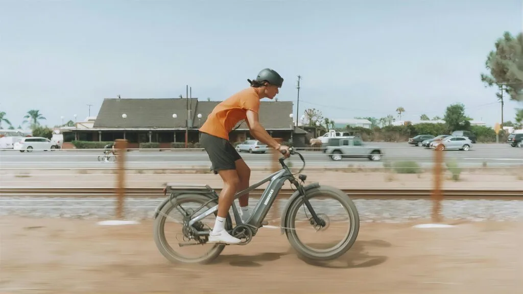A man rides an e-bike down a trail past a traffic jam.