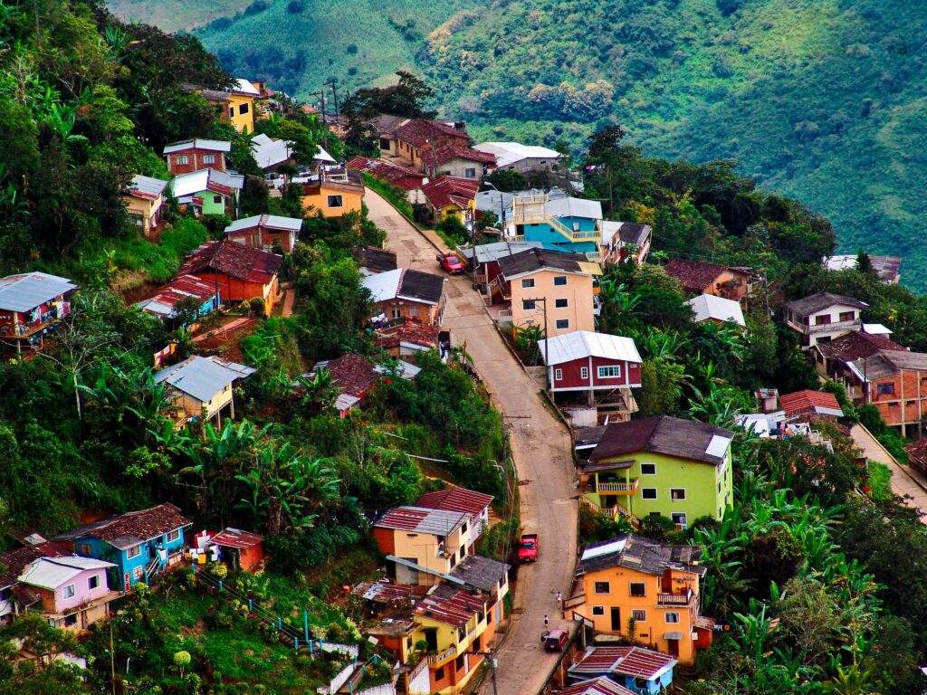 A road winds its way up a very steep mountain through multicoloured houses and forest in Zaruma, Ecuador.