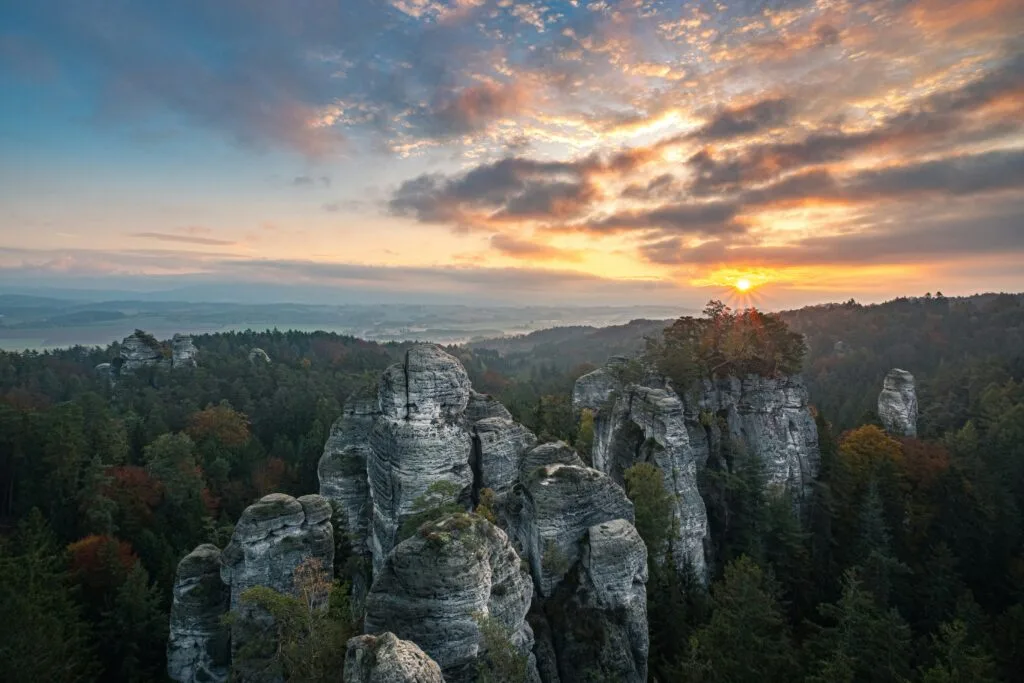 Huge rock formations poke through the top of a forest of pine trees in Bohemian Paradise near Turnov, Czechia.