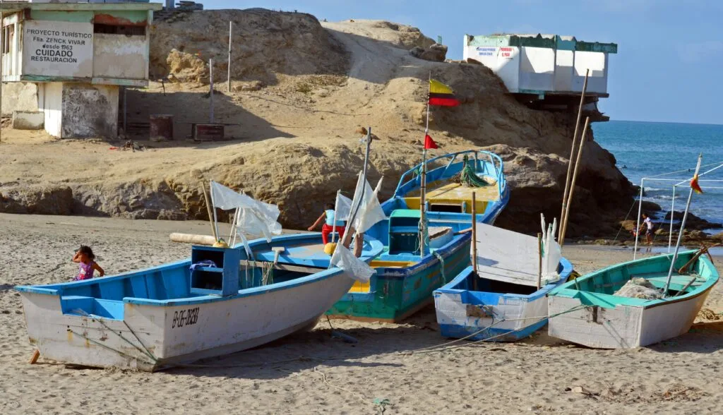 Small white and blue boats lie on a beach in Ecuador