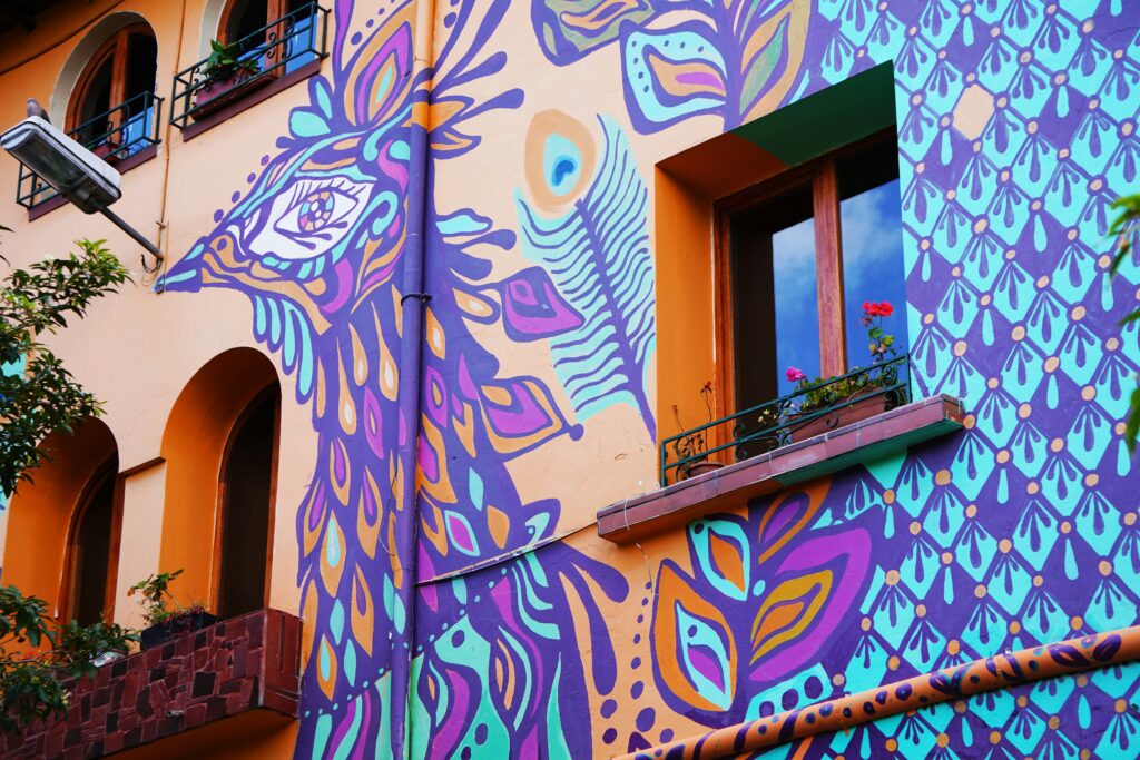 A mural showing a purple bird on the side of a house in La Calle del Arte, San Antonio de Ibarra, Ecuador.