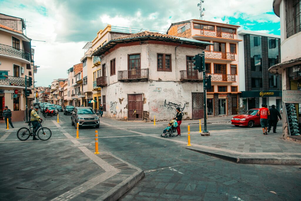 People and a cyclist wait to cross a road in Cuenca, Ecuador.