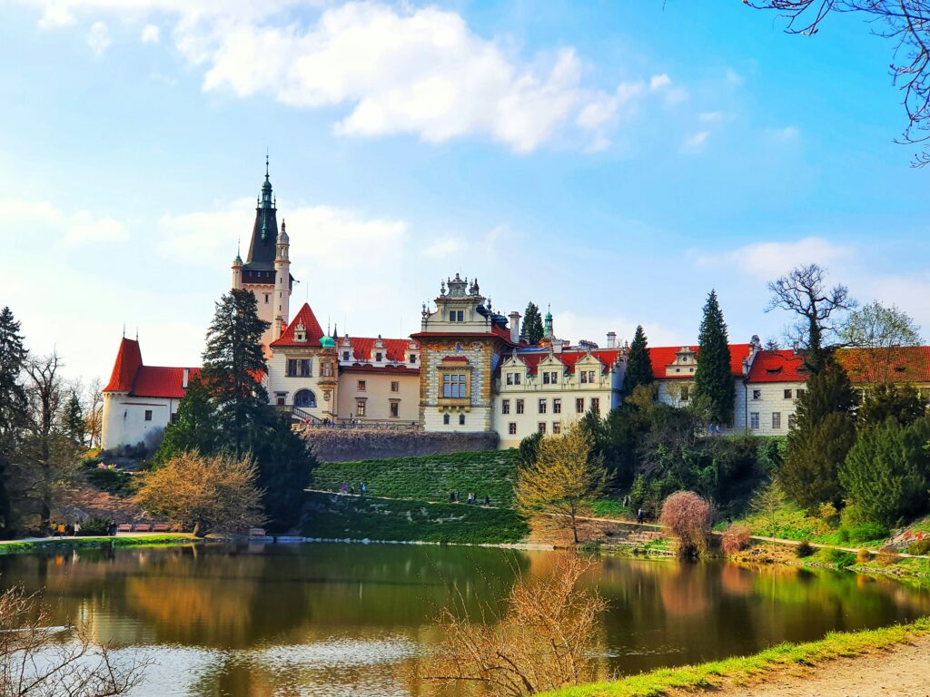 A large white castle and chateau is built on the edge of a lake near Prague — Průhonice.