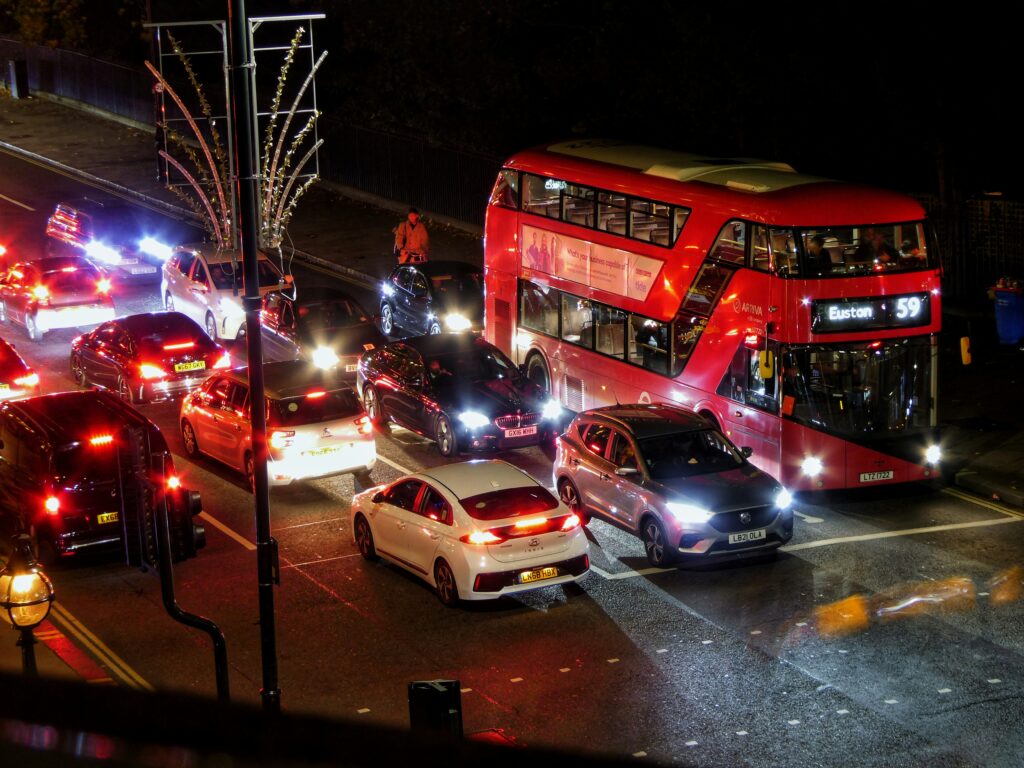 A red London bus sits and waits in a traffic jam. Wheely tyred city transport