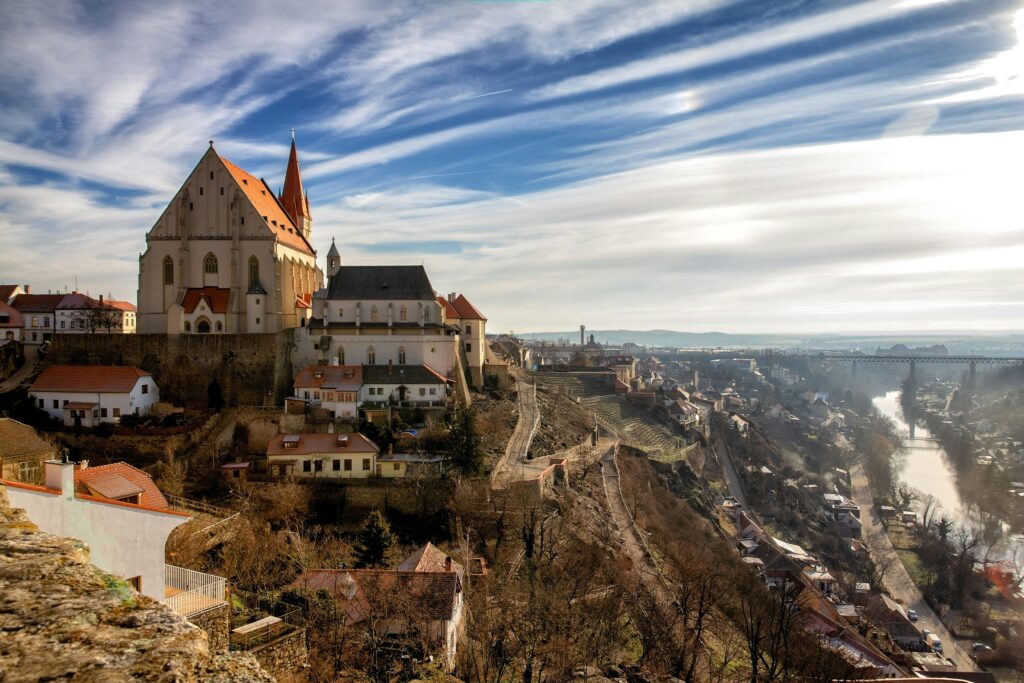 A church stands on the top of one side of a large valley filled with vineyards in Zojmo, Czechia. Wheely Tyred best time to visit Moravia