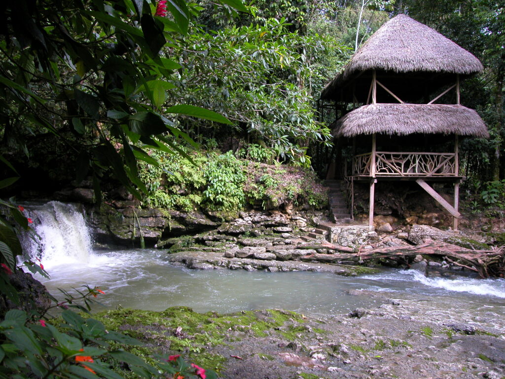 A wateerfall and rivver flow past a hut in Cascada de Latas near Tena, Ecuador