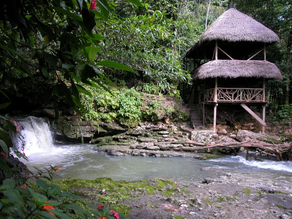 A wateerfall and rivver flow past a hut in Cascada de Latas near Tena, Ecuador