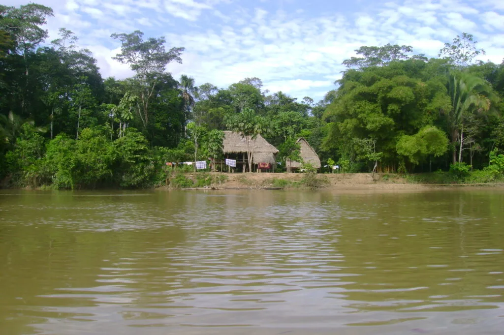 A wooden house sits on the edge of the Tiputini River, in Yasuní, Ecuador.