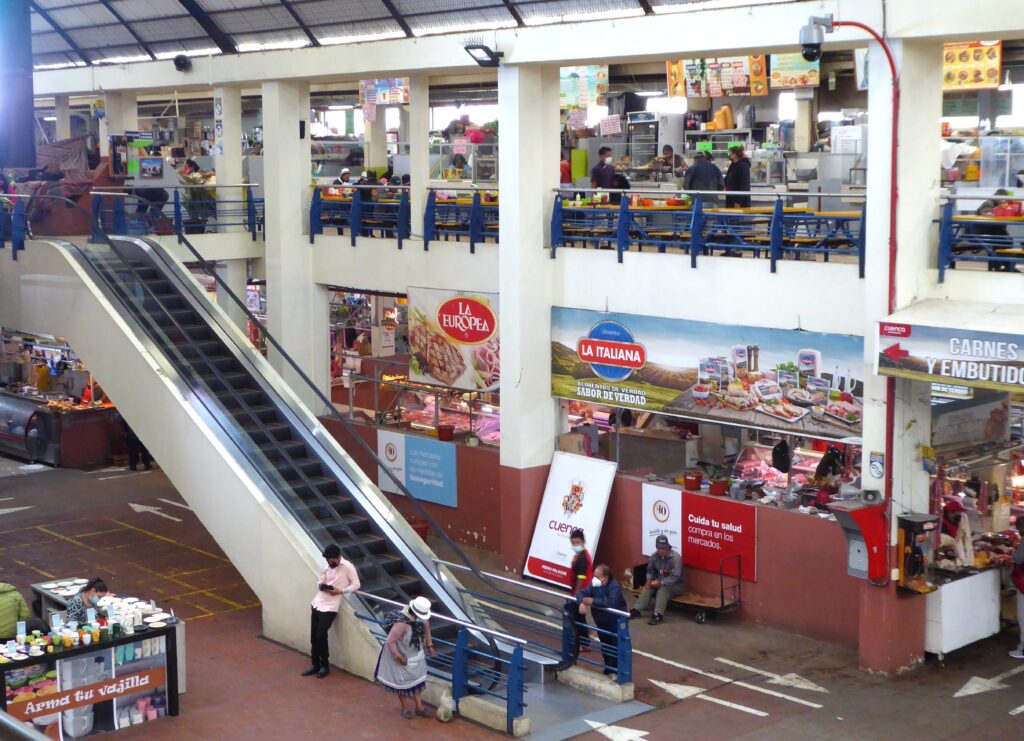 The interior of Mercado 10 de Agosto, with two floors and various vendors in Cuenca, Ecuador.