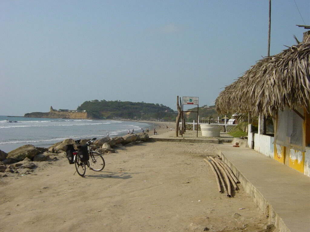 A bike with panniers is parked on a beach in Ecuador. Wheely Tyred Montañita safety