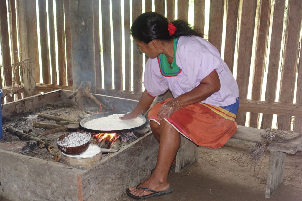 A Siona woman cooks in a wooden building in Cuyabeno, Ecuador.
