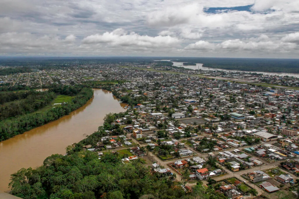 An aerial shot of Puerto Francisco de Orellana, Coca, with a brown river running through it.